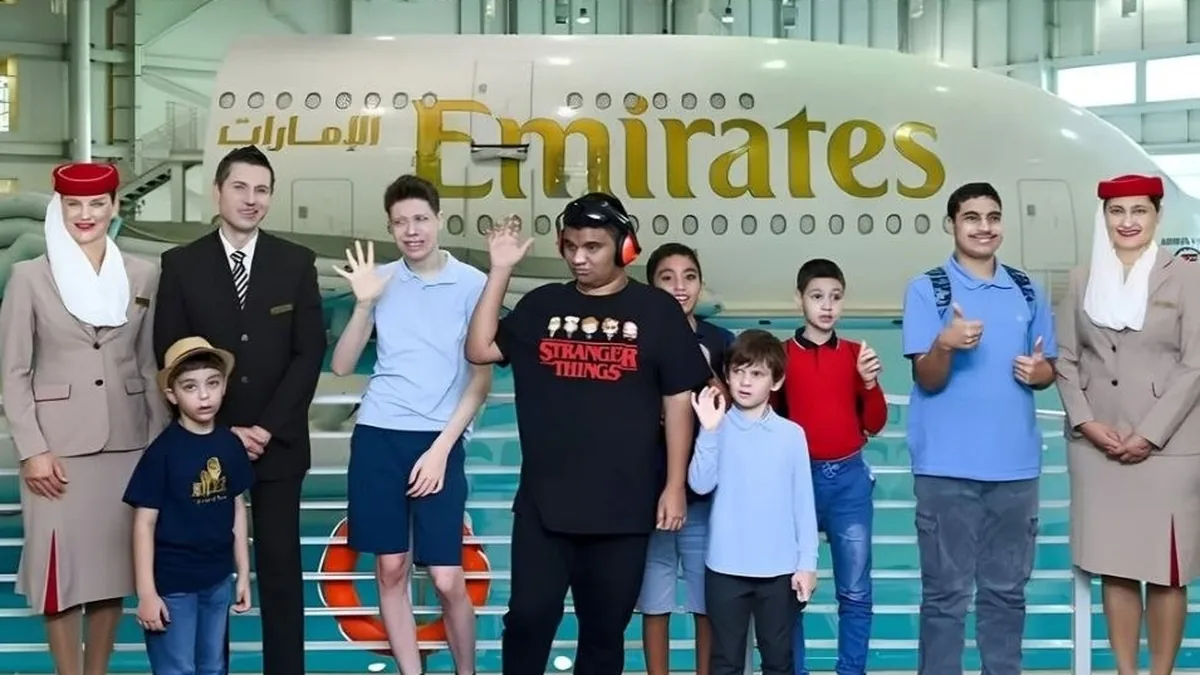 Grupo de jóvenes y personal de Emirates posa frente a un avión durante una actividad de familiarización con el viaje
