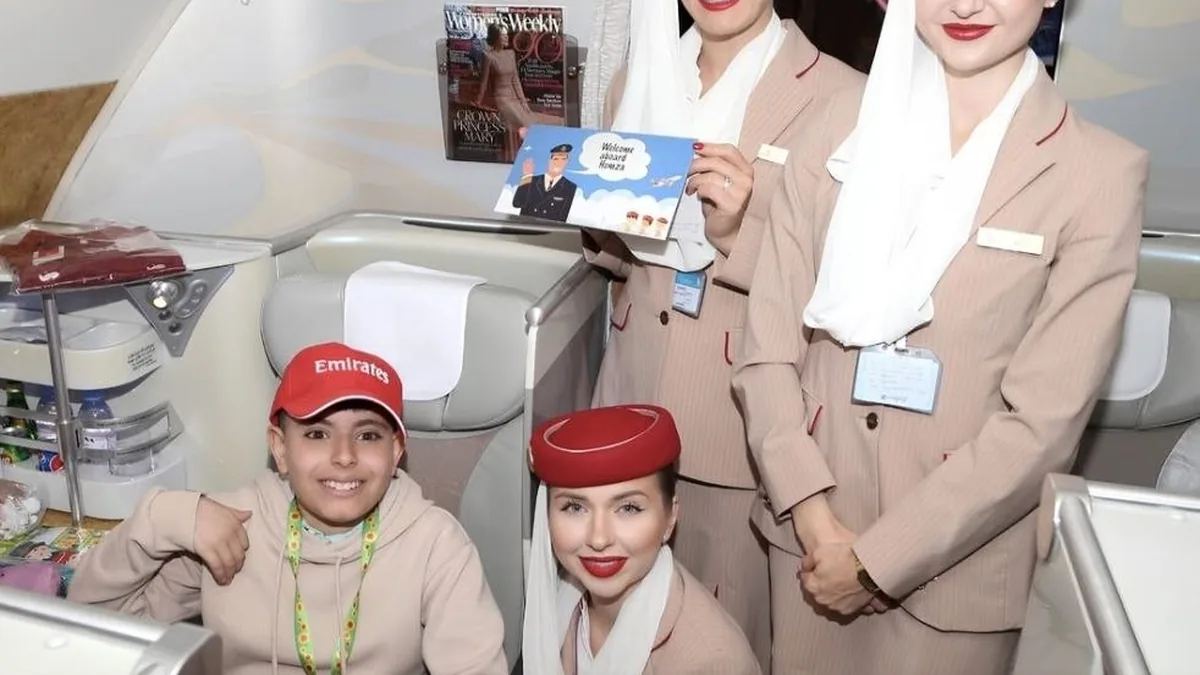 Joven posa junto a miembros de la tripulación de Emirates dentro de la cabina de pasajeros